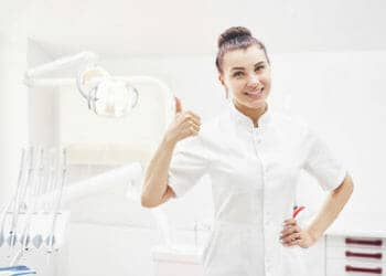 happy young female dentist with tools over medical Z3WGLGH 1