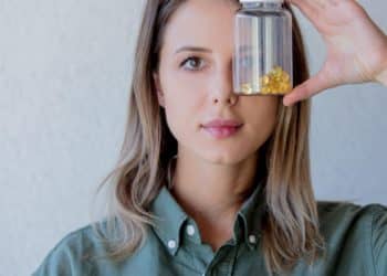 woman keeps transparent jar with pills at eye level 1 e1655719670583