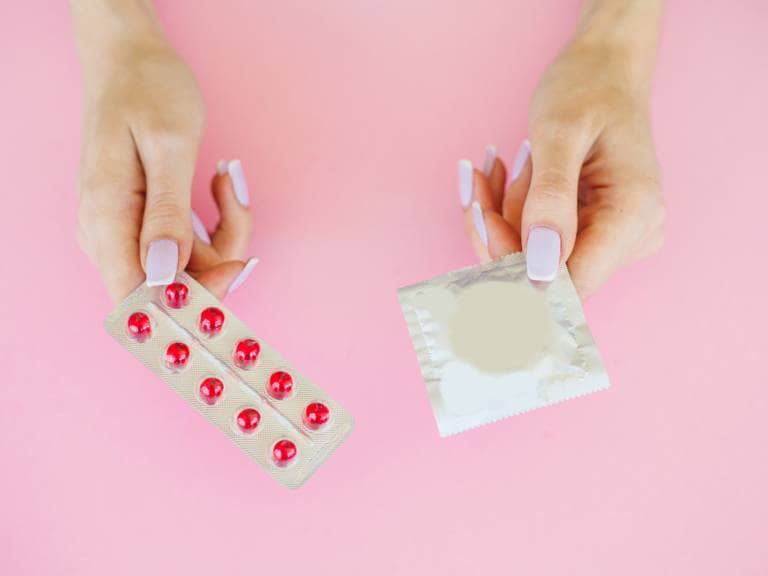 Hand showing condom and tablet medicine