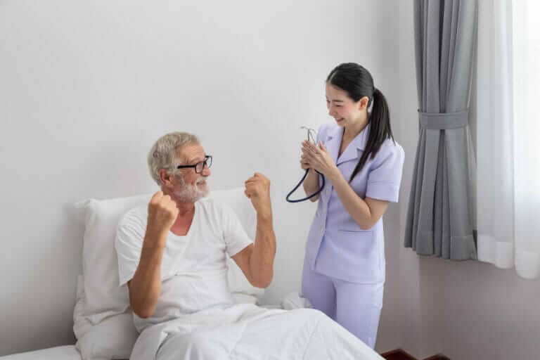 elderly man healthy rise fist up with happy nurse bedroom nursing home thumb up